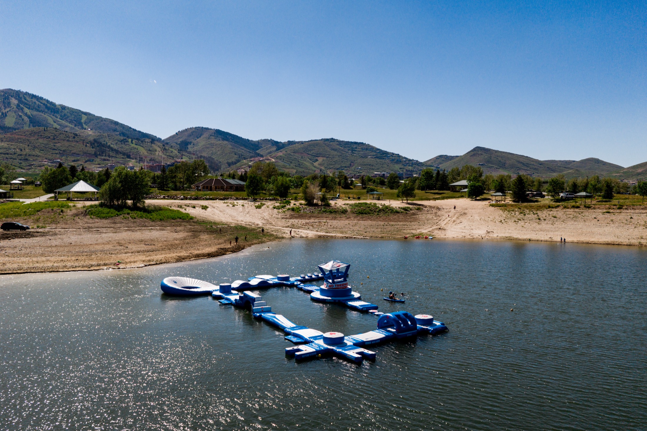 Aerial view of the Jordanelle Aqua Park floating obstacle course on Jordanelle Reservoir, framed by the Wasatch mountains